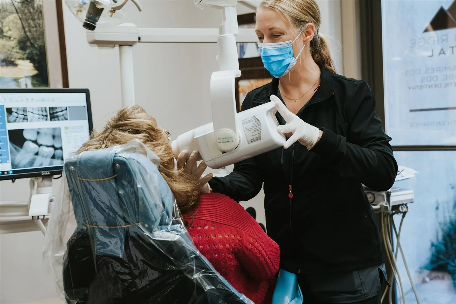 A hygienist positions the x-ray unit for a patient